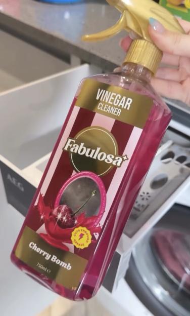 A hand holding a bottle of Fabulosa Cherry Bomb Vinegar Cleaner.