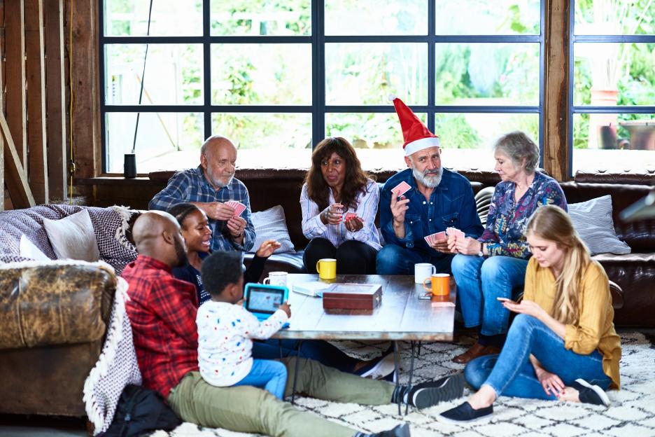 Family playing cards and using devices at Christmas.