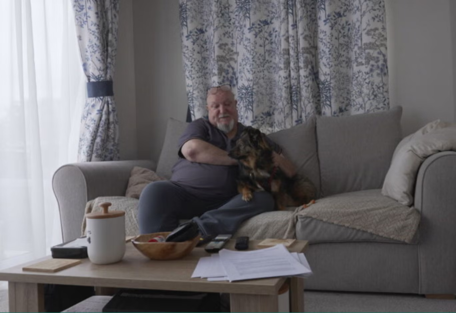 A man sitting on a couch with a dog on his lap.