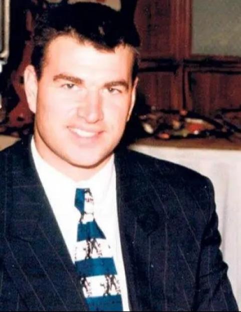 A man in a suit and a woman in a black top with a white collar smiling.