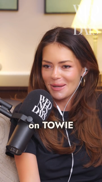 Woman wearing wired earbuds and a black shirt, speaking into a "Wednesdays" microphone.