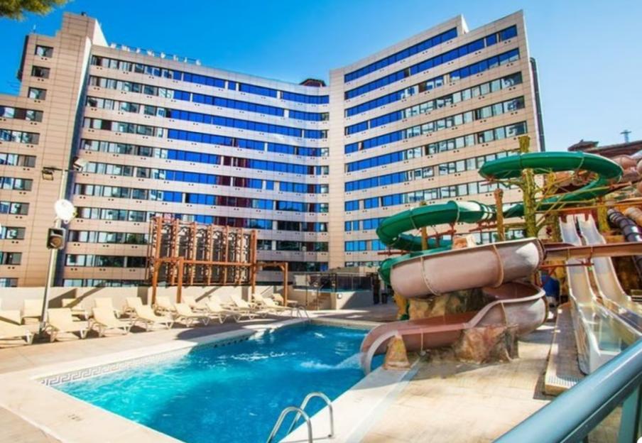 The Magic Aqua Rock Gardens hotel in Benidorm, Costa Blanca, Spain, featuring a swimming pool, lounge chairs, and water slides.