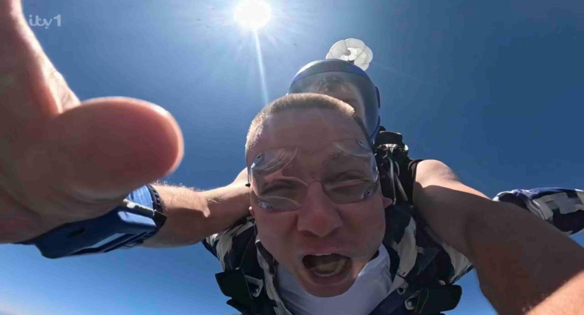 Aitch skydiving with a parachute open, and his mouth open, during "I'm A Celebrity… Get Me Out Of Here!"