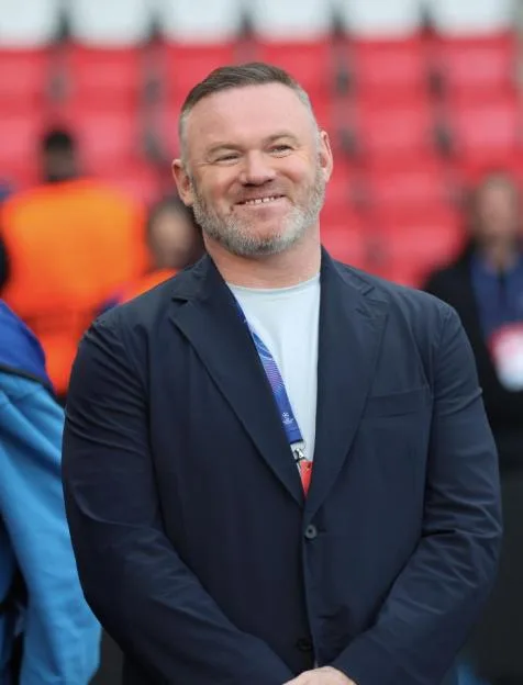 Wayne Rooney smiling in a stadium during the UEFA Champions League match.