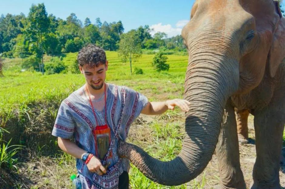 Calum Macdonald touching an elephant's trunk.