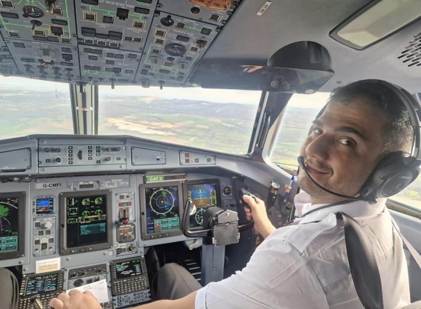 Arian Abbasi, a pilot, smiling from the cockpit of a plane.