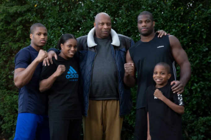 Five boxers of various ages and genders posing with fists raised.