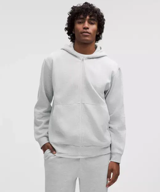 A young man wearing a gray zip hoodie and gray sweatpants.