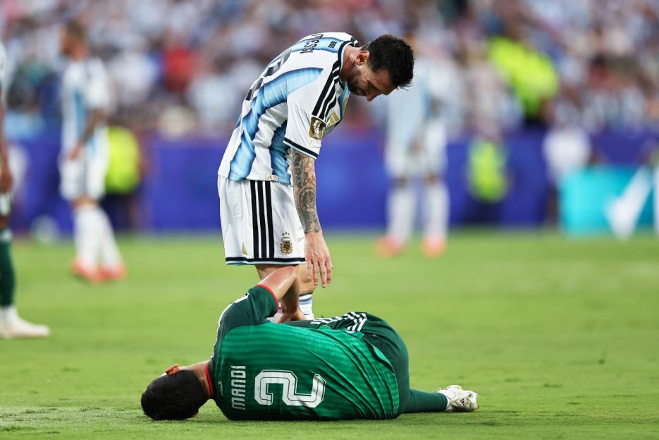 Lionel Messi standing over an Algerian player lying on the ground during a FIFA World Cup 2026 match.