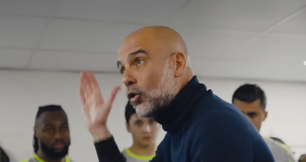 Pep Guardiola speaking passionately to his team in a dressing room.