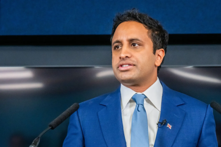 Vivek Ramaswamy speaking at a podium with microphones.