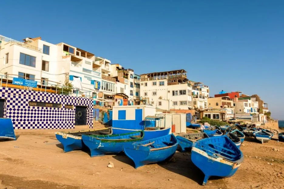 Blue wooden boats on the shore in Taghazout Village in Morocco.