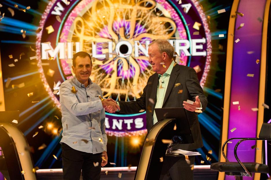 Roman Dubowski shaking hands with Jeremy Clarkson on the set of "Who Wants To Be A Millionaire" with confetti falling.