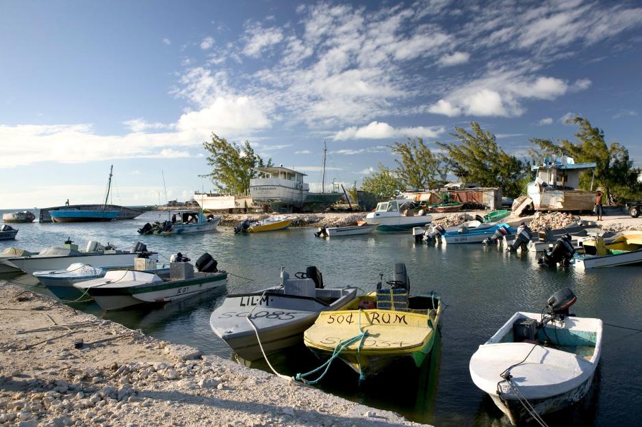 Boats docked in Cockburn Harbour, South Caicos Island, with larger vessels and a boatyard in the background.