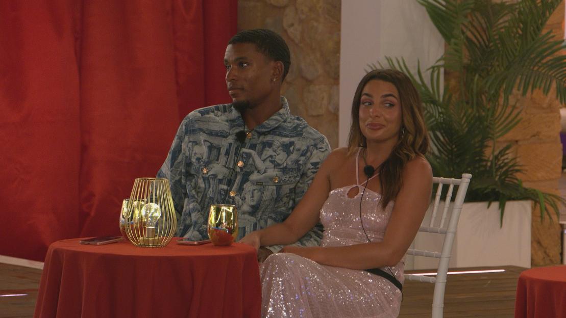 CACH and TONI from Love Island sitting at a table with drinks and phones.