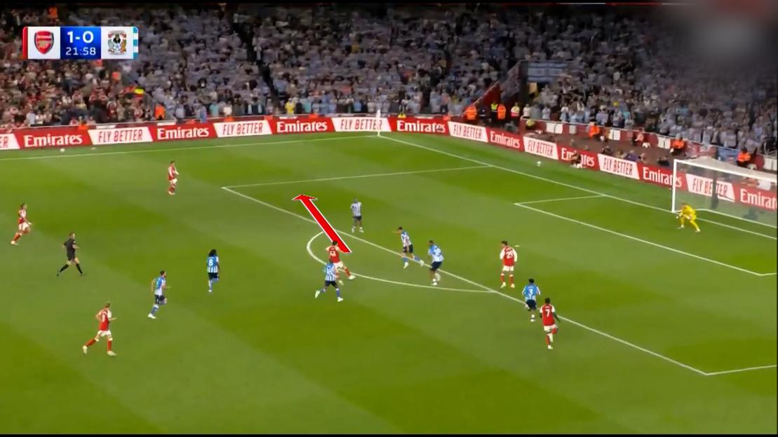 A soccer match with a player with a red jersey making a pass, with a red arrow indicating the ball's trajectory.