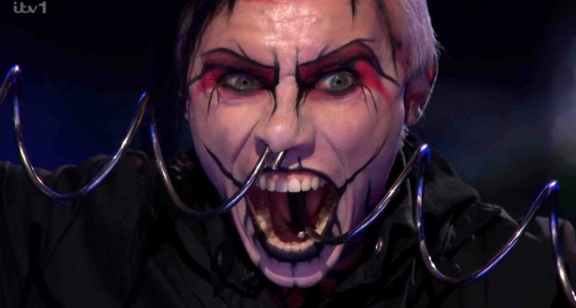 Auzzy Blood performing with face paint and metal rings in their nose and mouth.