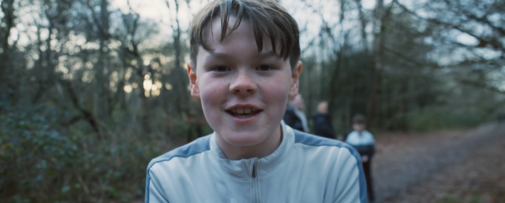 Mason smiling at the camera in a forest.