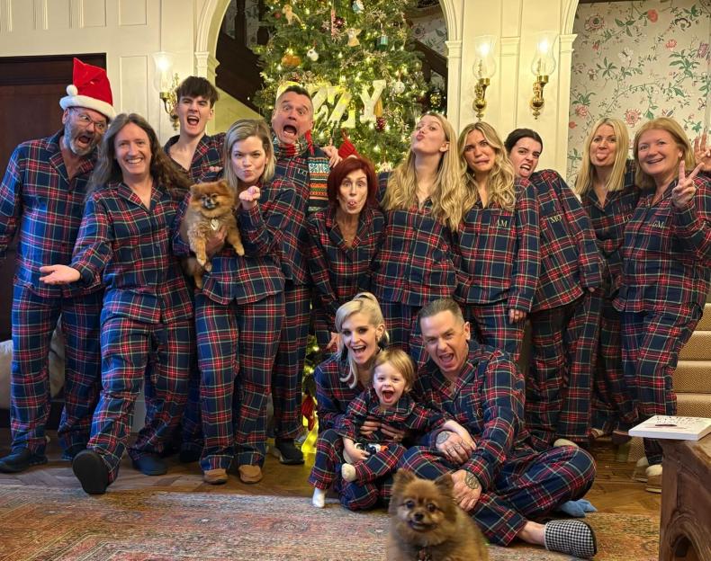 The Osbourne family in matching plaid pajamas in front of a Christmas tree.