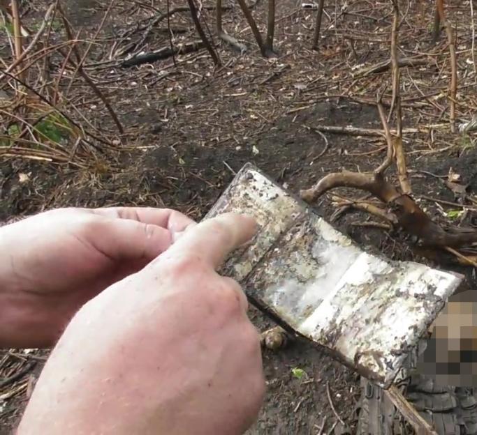 Hands pointing at a burned object with a blurred out portion.