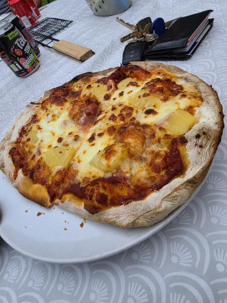 A freshly baked pizza with pineapple and ham toppings on a white plate.