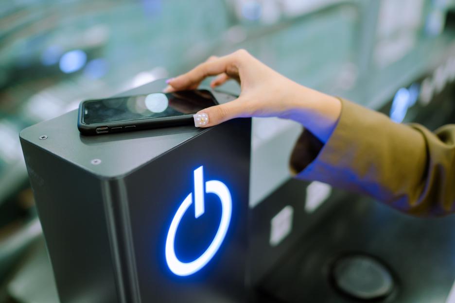 A woman's hand placing a smartphone on a wireless charger with a glowing power symbol.