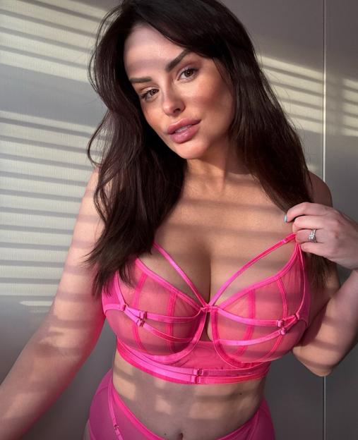 A woman in a pink bra and underwear looking at the camera.