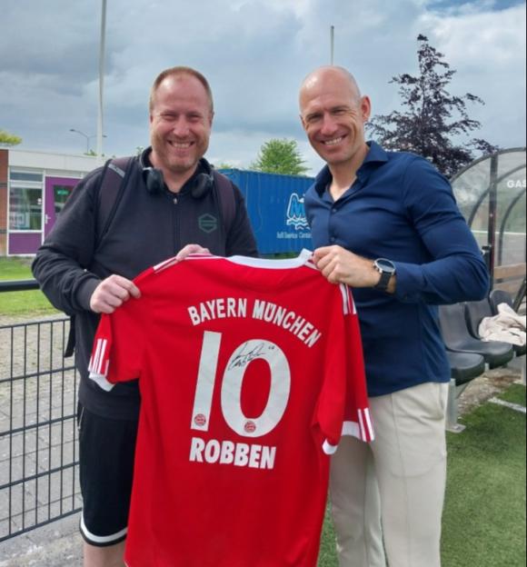 Two men holding a signed Arjen Robben #10 Bayern München jersey.