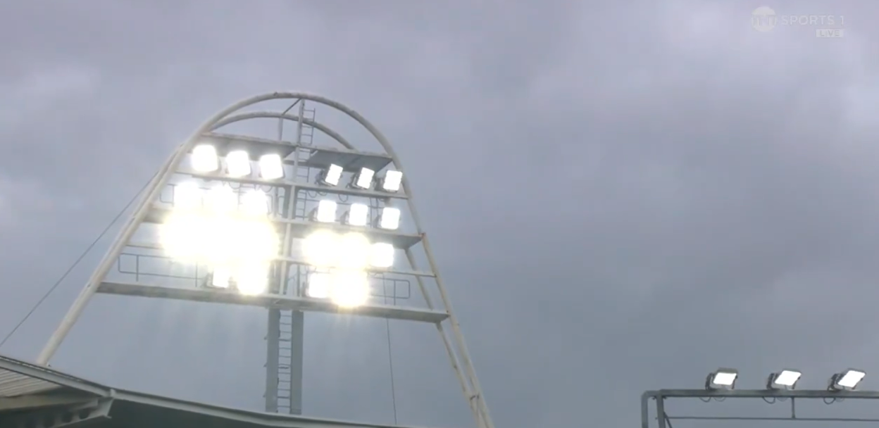 Stadium floodlights against a cloudy sky.