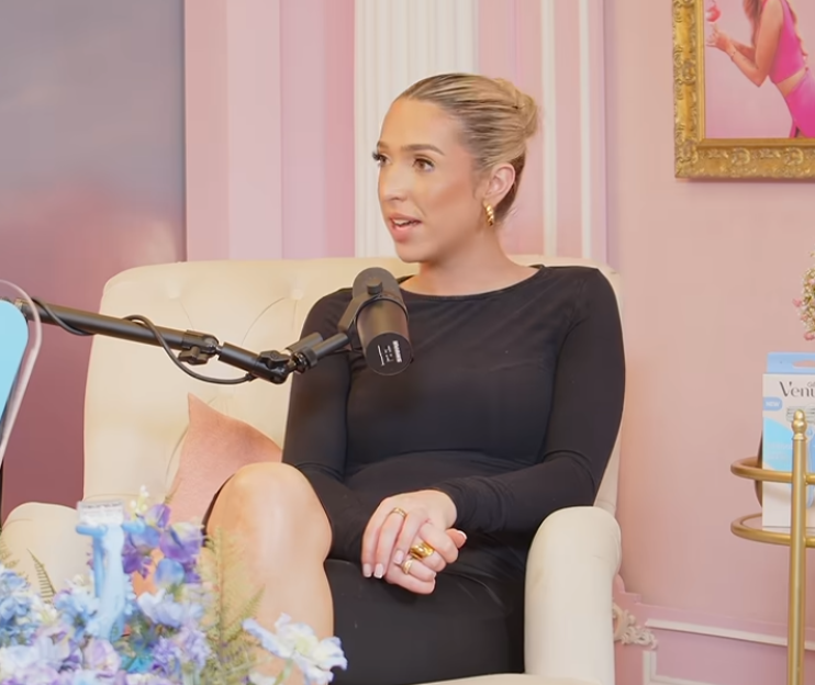 Woman in a black dress speaking into a microphone.