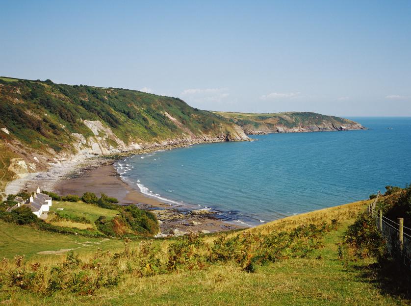 Man Sands beach, a secluded cove in Devon, UK, with a few white cottages near the shore.