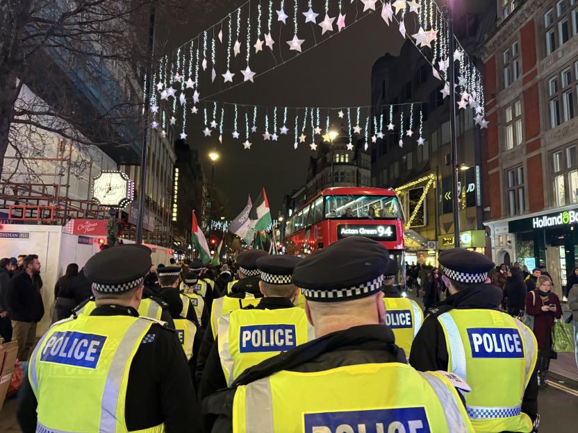 Police officers monitoring pro-Palestine protesters marching down Oxford Street in London.