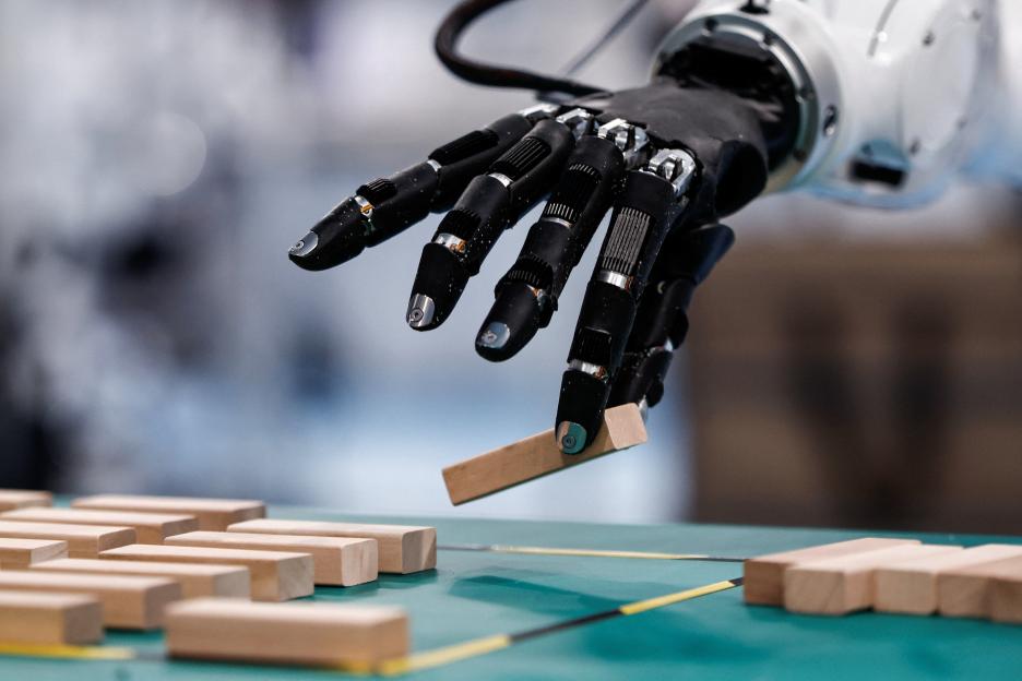 A humanoid robot hand manipulates a wooden block.