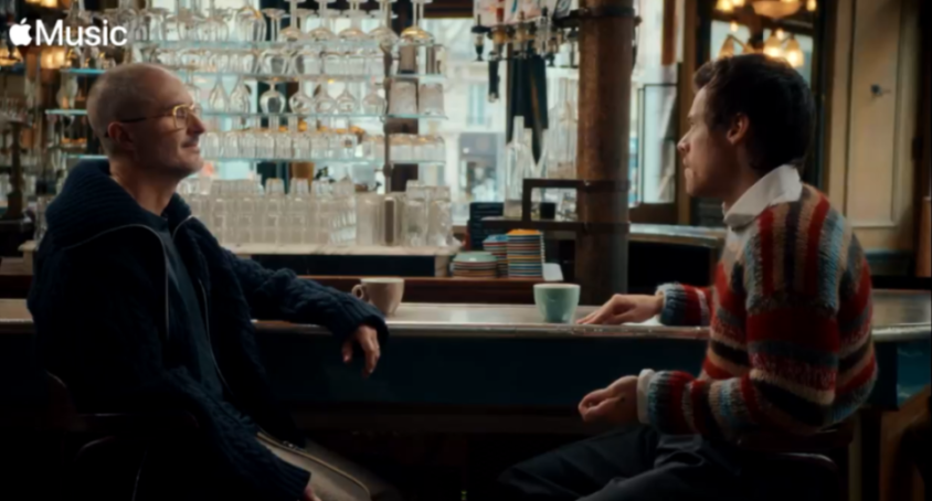 Two men sitting at a bar counter with coffee cups.