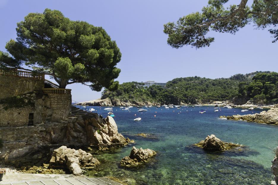 Cala Aigua Blava in Begur, Costa Brava, Spain, with boats anchored in the blue sea.