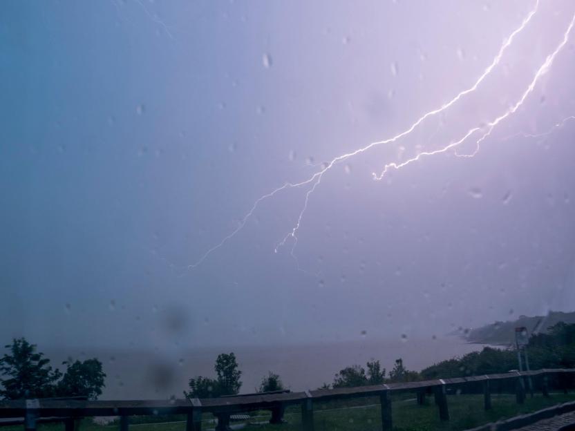 Lightning strike over Minster on Sea, Kent, seen through a rain-streaked window.