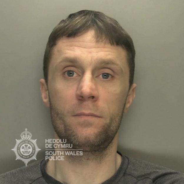 Mugshot of a man with short brown hair and a beard looking directly at the camera.