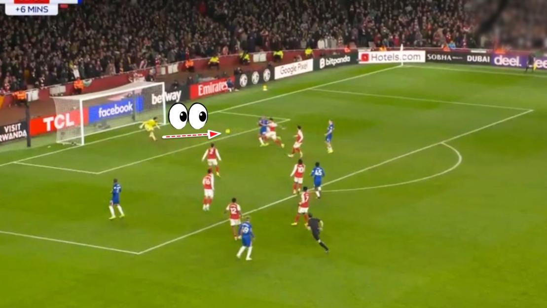 Soccer game in progress, with a ball moving towards the goal, indicated by a dashed line and arrow.