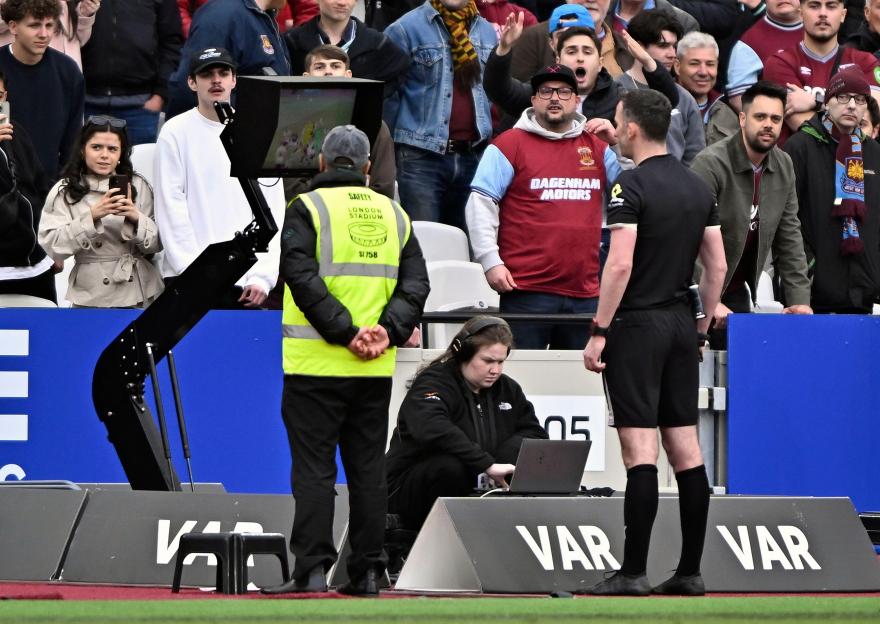 Referee Chris Kavanagh watches the VAR screen during a football match.