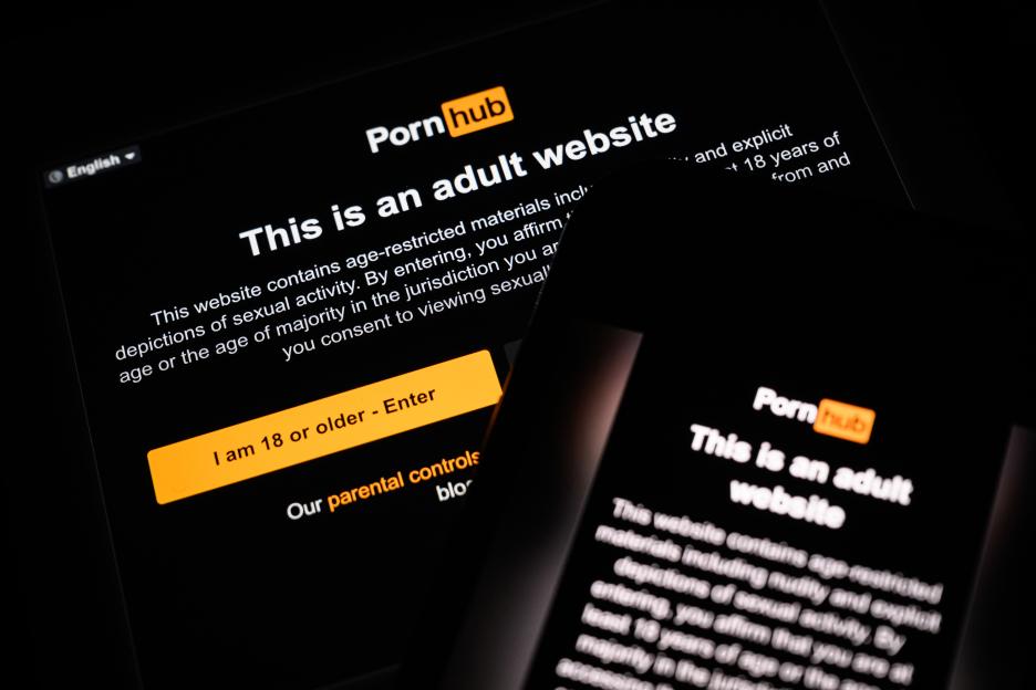 Age-restriction warning screens for Pornhub displayed on two digital screens.