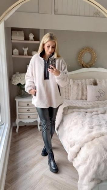 Stacey Solomon in her bedroom, wearing a cream fluffy jumper, black faux leather trousers, and black boots.
