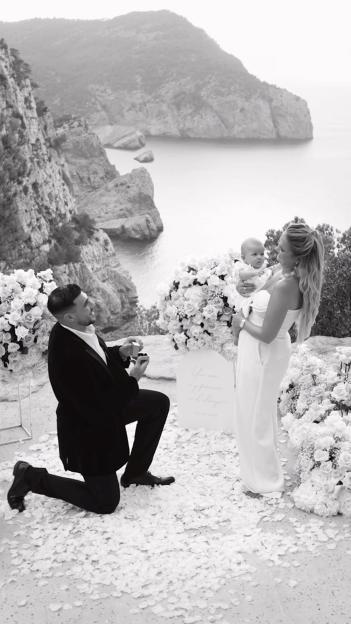 Tommy Fury proposing to Molly-Mae Hague while she holds their baby, with a cliffside ocean view.
