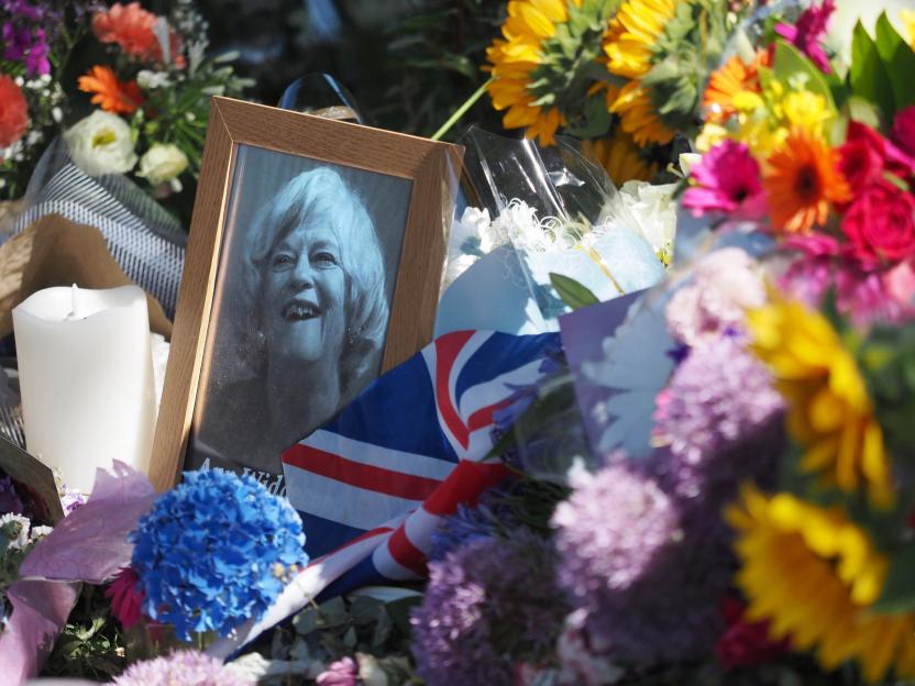 A framed photo of Ann Widdecombe amidst floral tributes and a Union Jack flag.