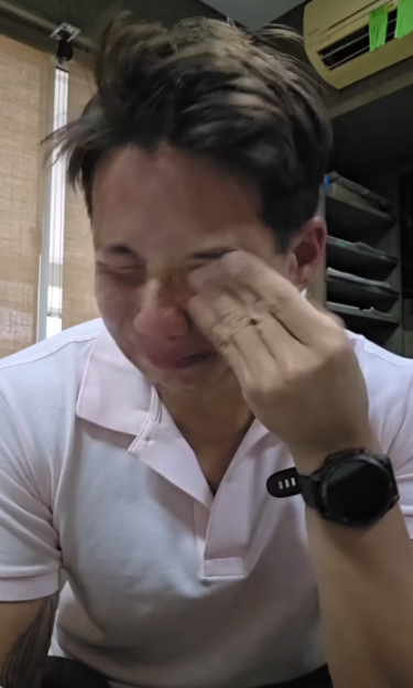 Siranudh Scott crying as he rubs his eye, wearing a white polo shirt and a watch on his left wrist.