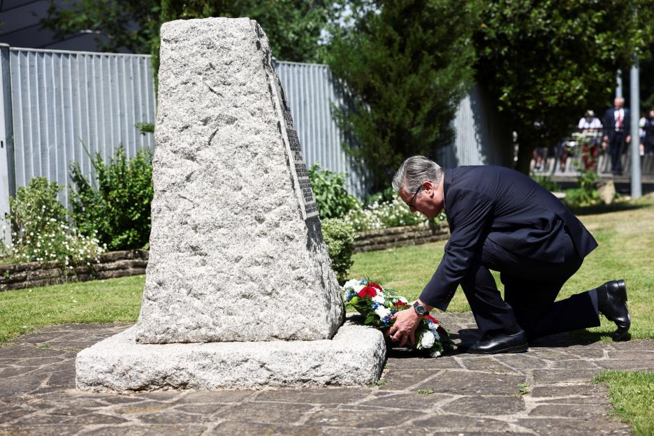 Donald Tusk laying a wreath at a monument.