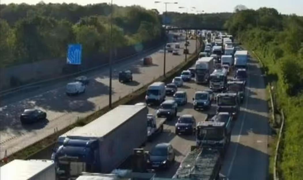 Aerial view of a multi-lane highway with heavy traffic, including cars and trucks, on both sides of the road.
