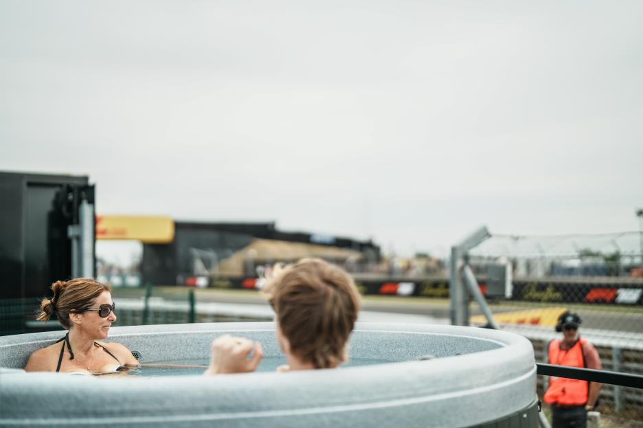 Two people in a hot tub watching a race at The Pop-Up Hotel, Silverstone.