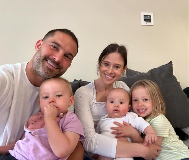 Jamie Jewitt, Camilla Thurlow, and their three children smile while sitting on a couch.