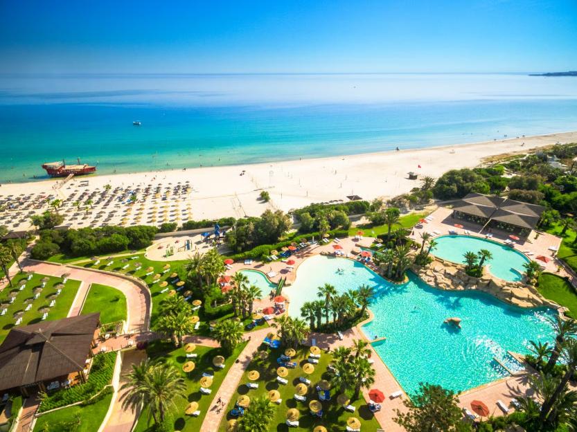 Aerial view of the Sahara Beach Aquapark Resort with a sandy beach and blue ocean in the background.