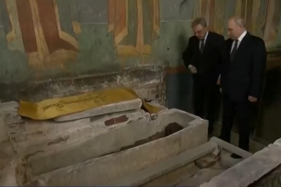 Two men in dark suits look into a stone sarcophagus containing the remains of Dmitry Donskoy, a medieval warrior prince.